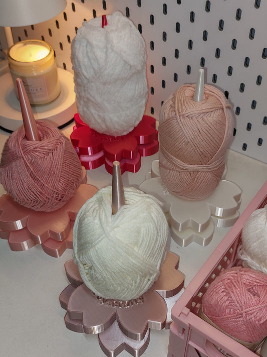 Yarn balls on yarn holders with a candle and yarn organized in the background